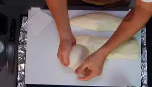 After resting take out the dough from the bowl and with a little olive oil divide the dough into three parts