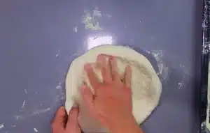 Place the dough on the flour and then take off the table and press it with your hands to make bigger, you should be careful that there is no air in it.