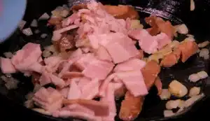 Now cut an onion with two sausages and three pieces of bacon and fry them well in a pan with vegetable oil for Texas Roadhouse Cheese Fries Recipe.